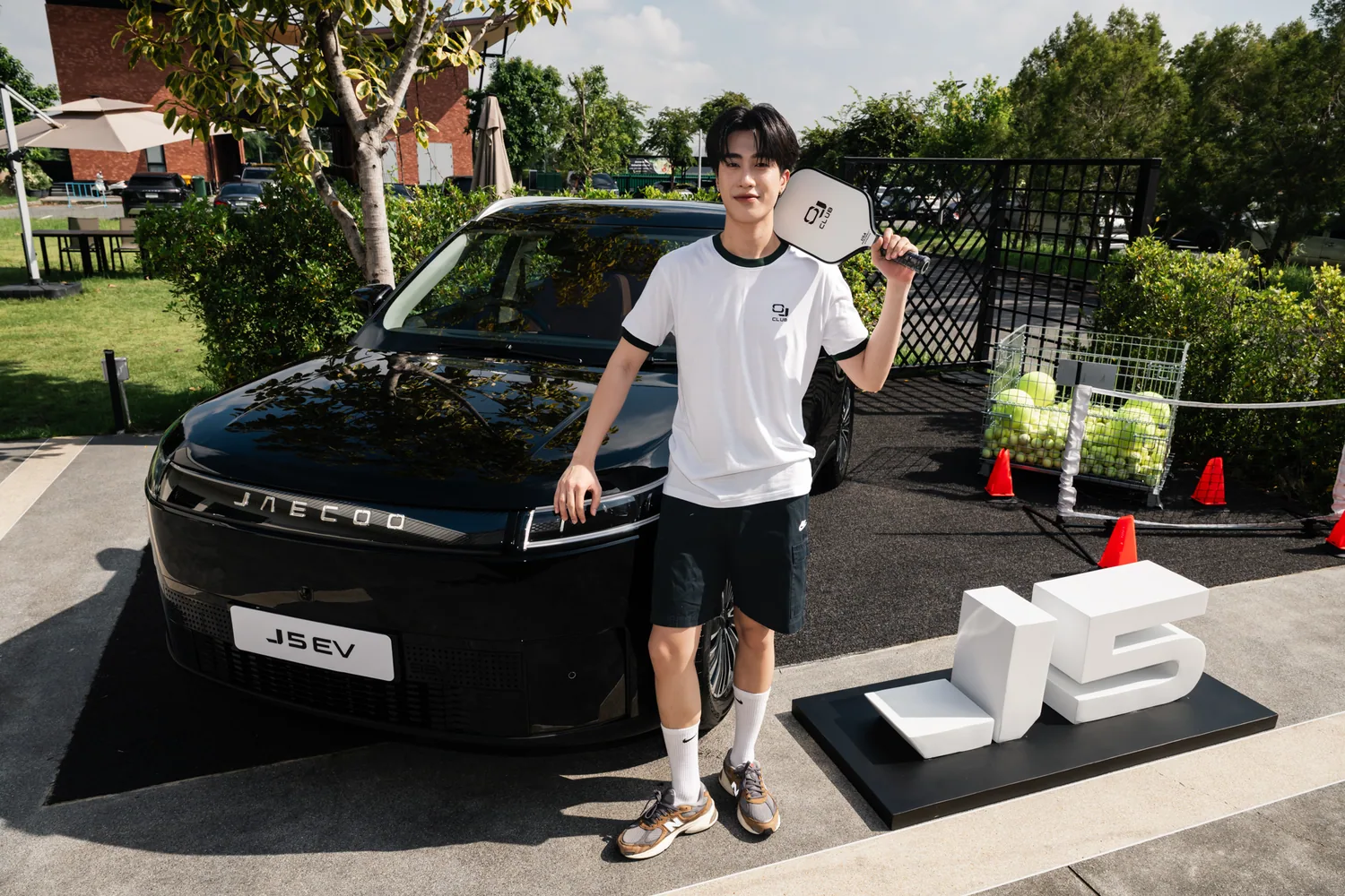 ผู้เข้าร่วมงานถือไม้ Pickleball หน้า JAECOO 5 EV