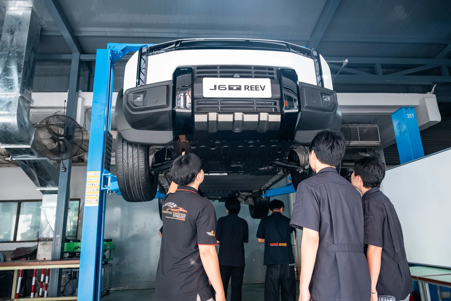 นักศึกษาสำรวจใต้ท้องรถ JAECOO 6T REEV ที่ถูกยกลอย