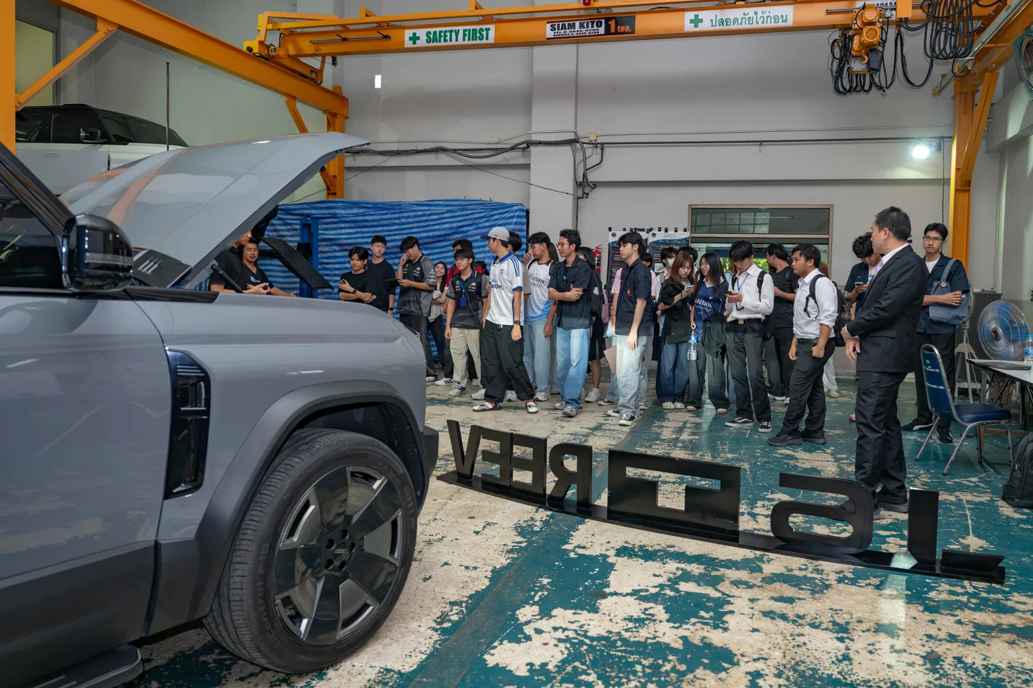 นักศึกษามหิดลยืนฟังการบรรยายข้างรถ JAECOO 6T REEV