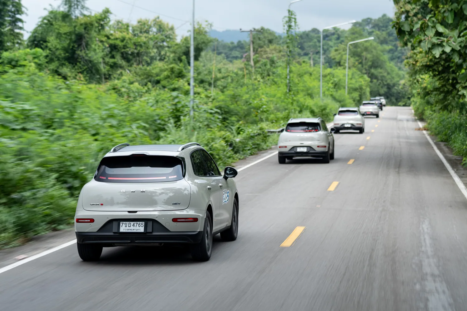 ขบวน GWM ORA 5 HEV วิ่งบนถนนท่ามกลางธรรมชาติ