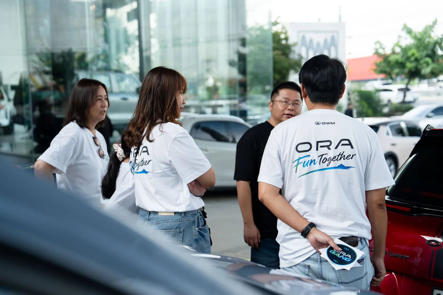 กลุ่มผู้ร่วมกิจกรรมสวมเสื้อ ORA ยืนพูดคุยกัน
